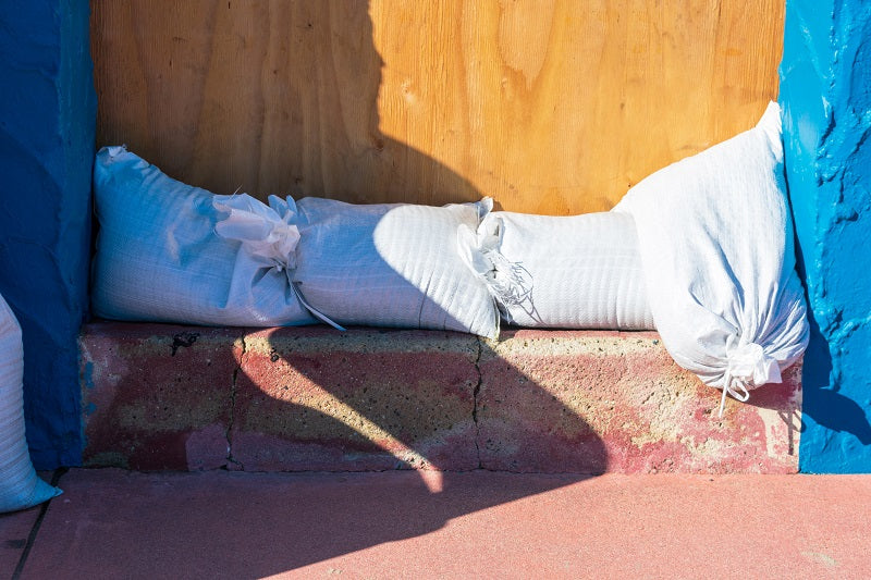 white sandbags in front of door protecting from flood water