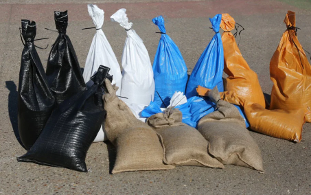 An image of filled sandbags in a variety of materials and colours