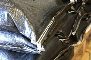 A closeup of a heavy duty UV-protected woven polypropylene black prefilled sandbag