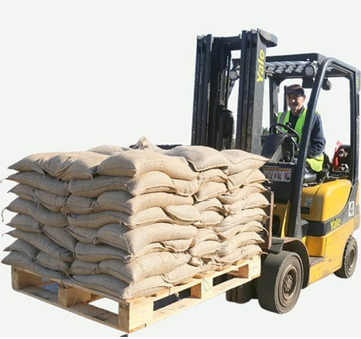 a forklifts truck driver with a pallet of sandbags