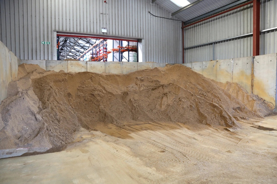 A large pile of sandbag sand in an enclosed warehouse