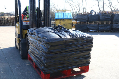 A trust driver with a pallet of black uv protected woven pp sandbags