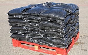 A pallet of heavy duty UV-protected woven polypropylene black prefilled sandbags